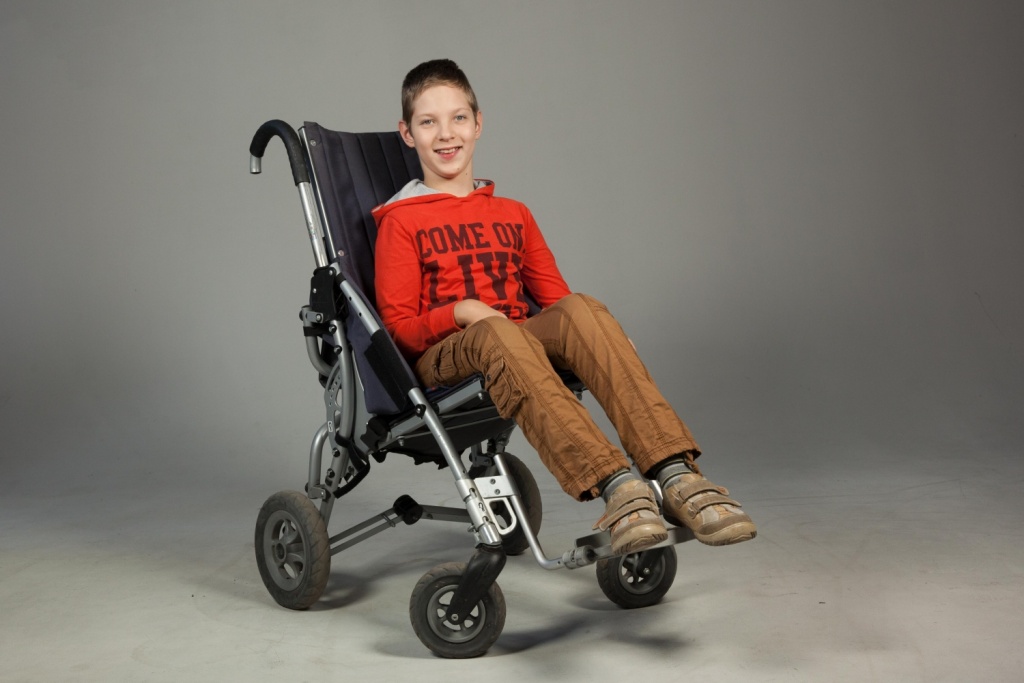 Подросток с церебральным параличем в специальной коляске